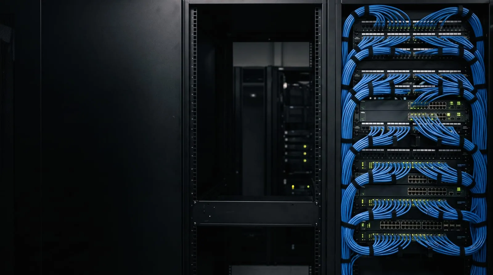 A dark server cabinet with blue patch cables and glowing status lights on the right